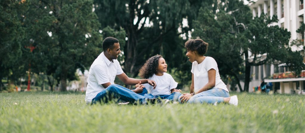 family sitting in grass having a picnic